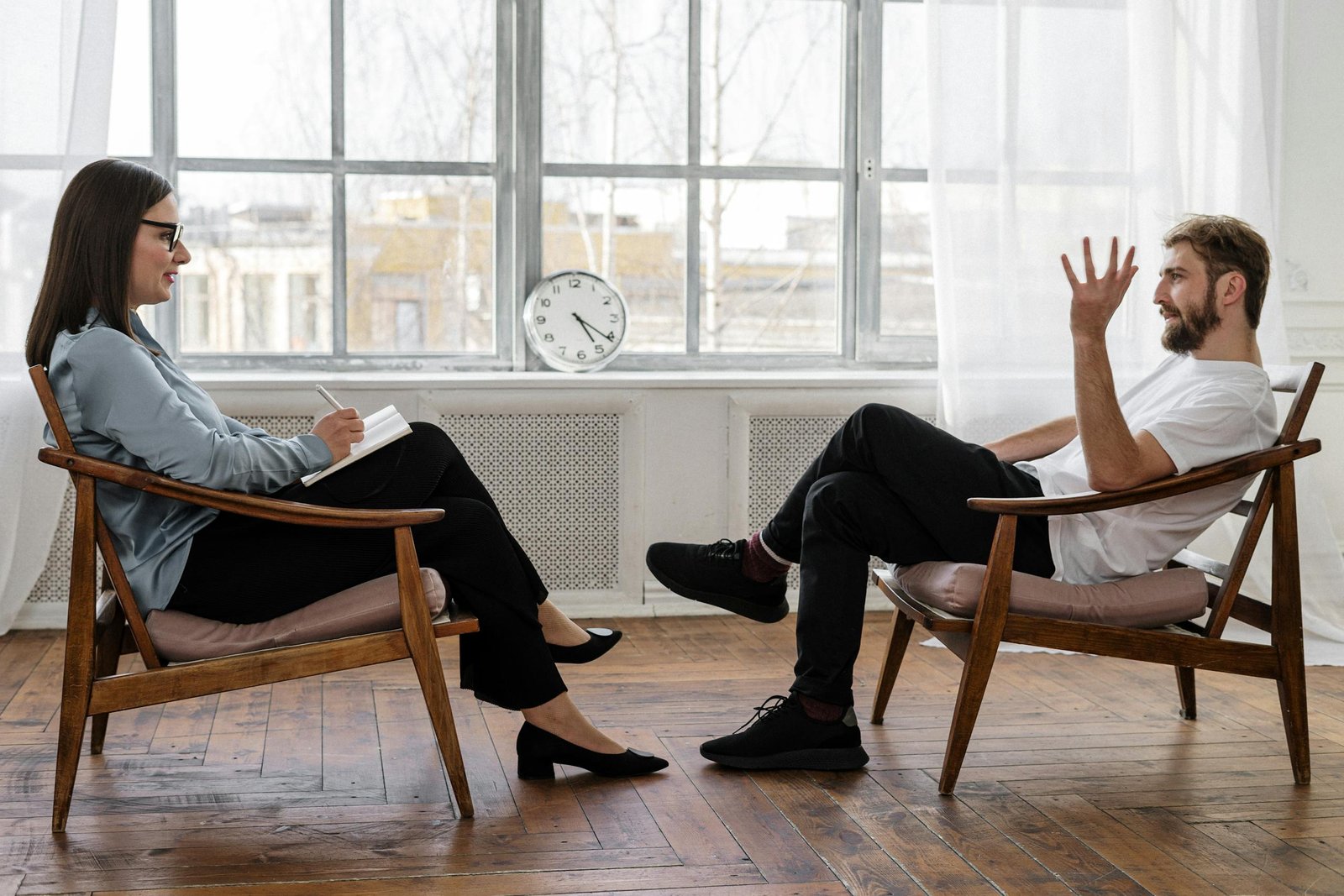 person in black pants and black shoes sitting on brown wooden chair 4101143 scaled 1